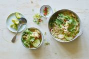 Eine Schale mit asiatischer Hühnersuppe und Schälchen mit Gemüse, bzw. Gewürzen Eine Schale mit asiatischer Hühnersuppe und Schälchen mit Gemüse, bzw. Gewürzen